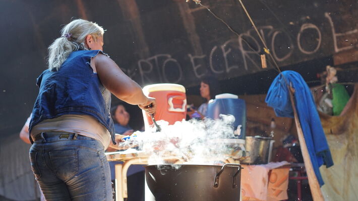 Mulher serve comida sob ponte em à moradores de rua em Campo Grande 