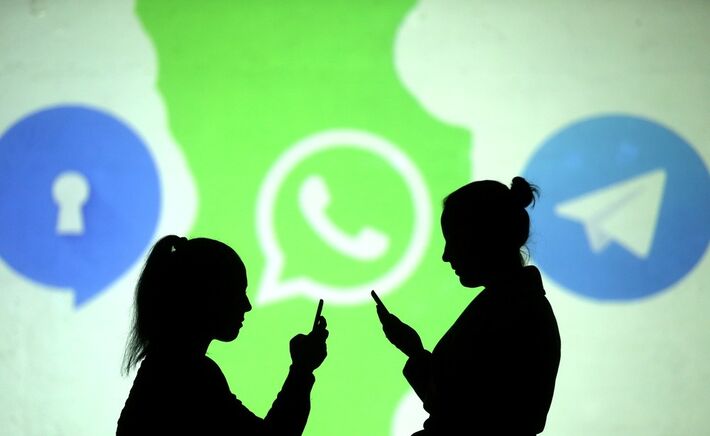 Pessoas utilizam celulares diante de projeção dos logos do Signal, WhatsApp e Telegram em foto ilustrativa  Foto: Dado Ruvic/Reuters