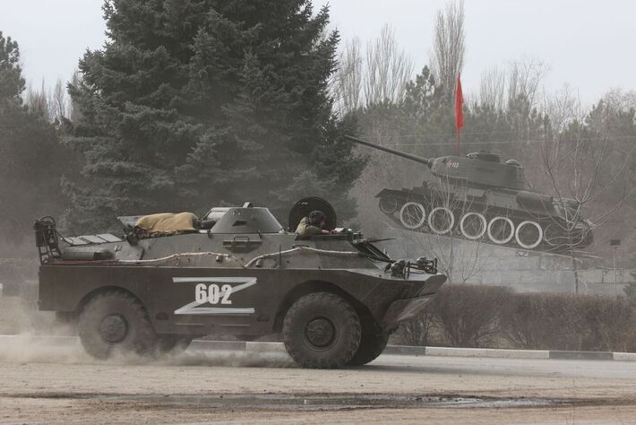 Veículo militar do exército russo com a letra 'Z' sobre ele passam por um monumento exibindo um tanque de época soviética, depois que o presidente russo Vladimir Putin autorizou uma operação militar no leste da Ucrânia, na cidade de Armyansk, Crimeia, 24 