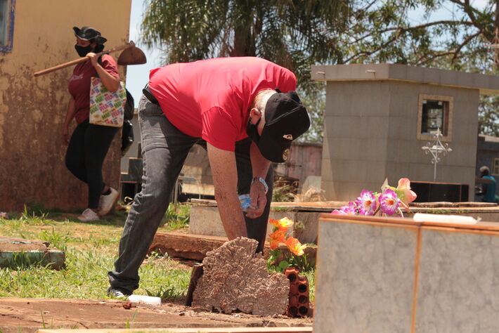 Homem acende vela para ente querido durante o dia de finados de 2021. Foto: Tero Queiroz