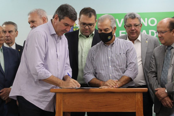 O pré-candidato ao Governo do Estado, Eduardo Riedel, assina documento de aporte financeiro à Saúde em Dourados. Ao lado, está Reinaldo Azambuja (PSDB); ao fundo, está o prefeito da cidade, Alan Guedes. Foto: Reprodução 