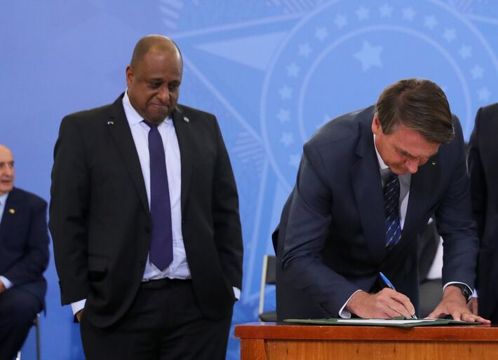  Marcelo Reis Magalhães observa Jair Bolsonaro assinar documento.  Foto: Isac Nóbrega/PR