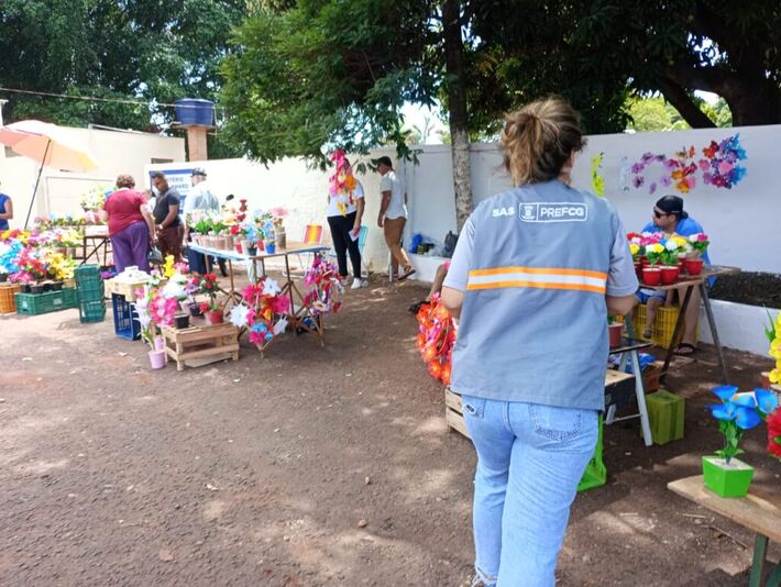 Servidora da SAS com colete de identificação realiza fiscalização em frente a um cemitério onde estão vendedores ambulantes de flores. Foto: Reprodução