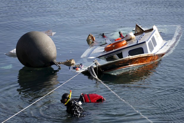 Oficiais da Guarda Costeira grega resgatam corpo após acidente com bote de refugiados perto da ilha de Lesboas (Foto: Giorgos Moutafis/Reuters)