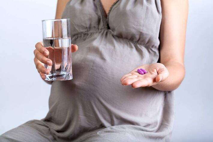 Mulher grávida tomando comprimidos