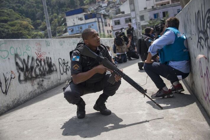Polícias e jornalistas se protegem durante operação para combater traficantes de drogas fortemente armados na favela da Rocinha, no Rio de Janeiro, em 22 de setembro de 2017