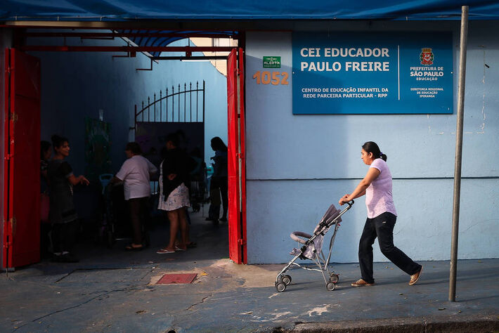mulher empurra carrinho de bebê em direção à porta de creche Creche municipal em Santa Cecília, São Paulo