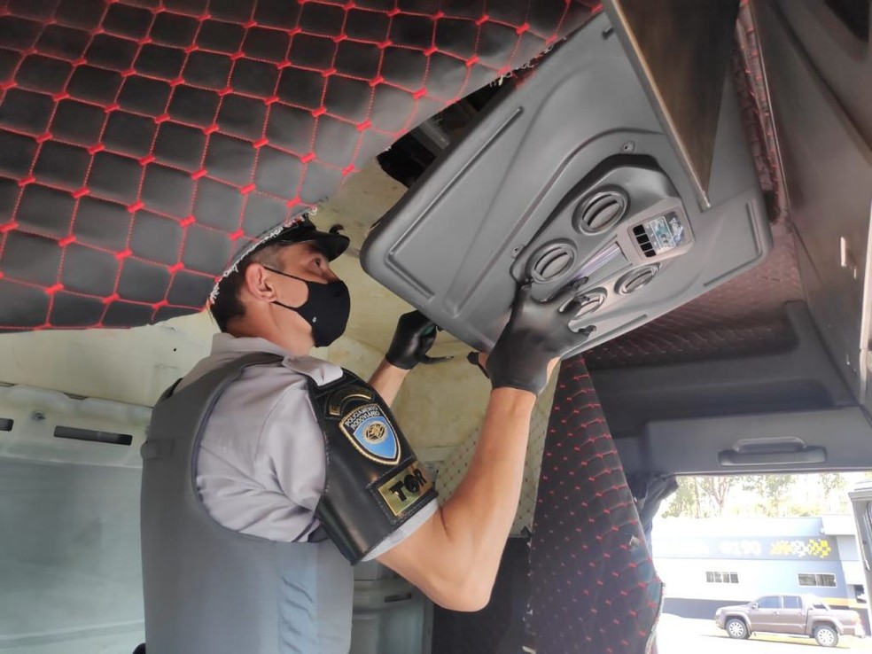 Policial recorta fundo falso em cabine de descobre cédulas em dólares e reais. Foto: PMR-SP