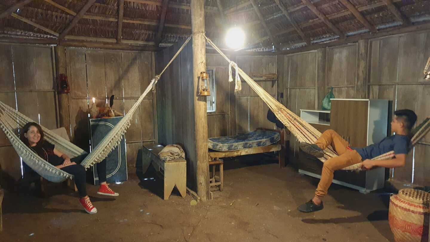 Fabiane Fernandes e Luan Iturv deitados em redes dentro da Casa indígena tradicional construída para a novela Terra e Paixão. Foto: Arquivo Pessoal ao TeatrineTV